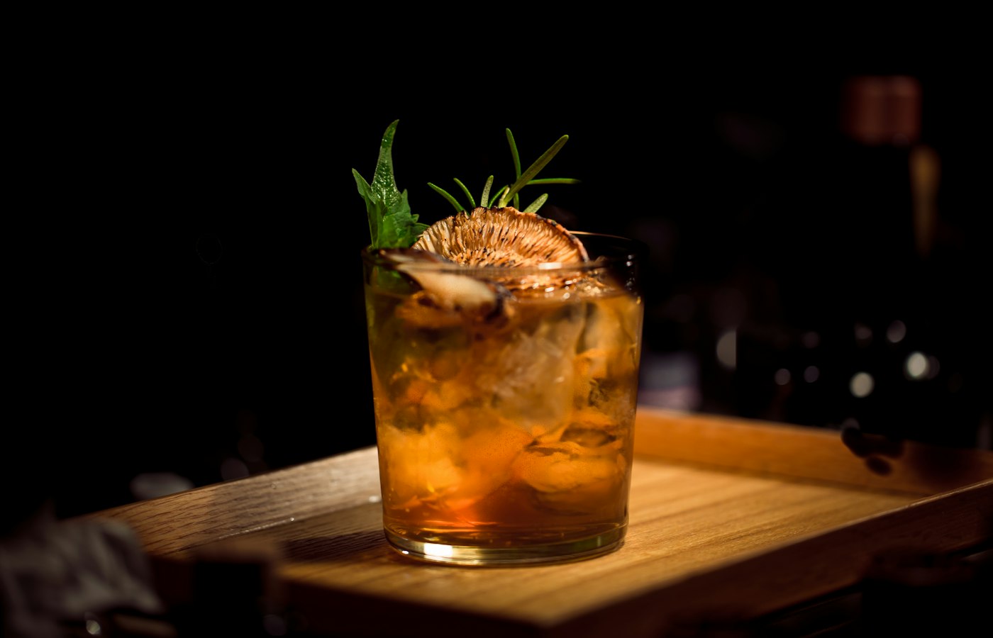 Garnished craft cocktail with dried citrus wheel and fresh herbs